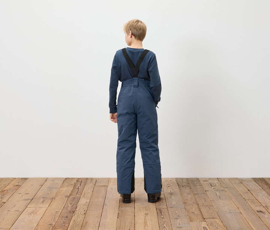 Egy fiú háttal áll, kék kantáros nadrágot visel.