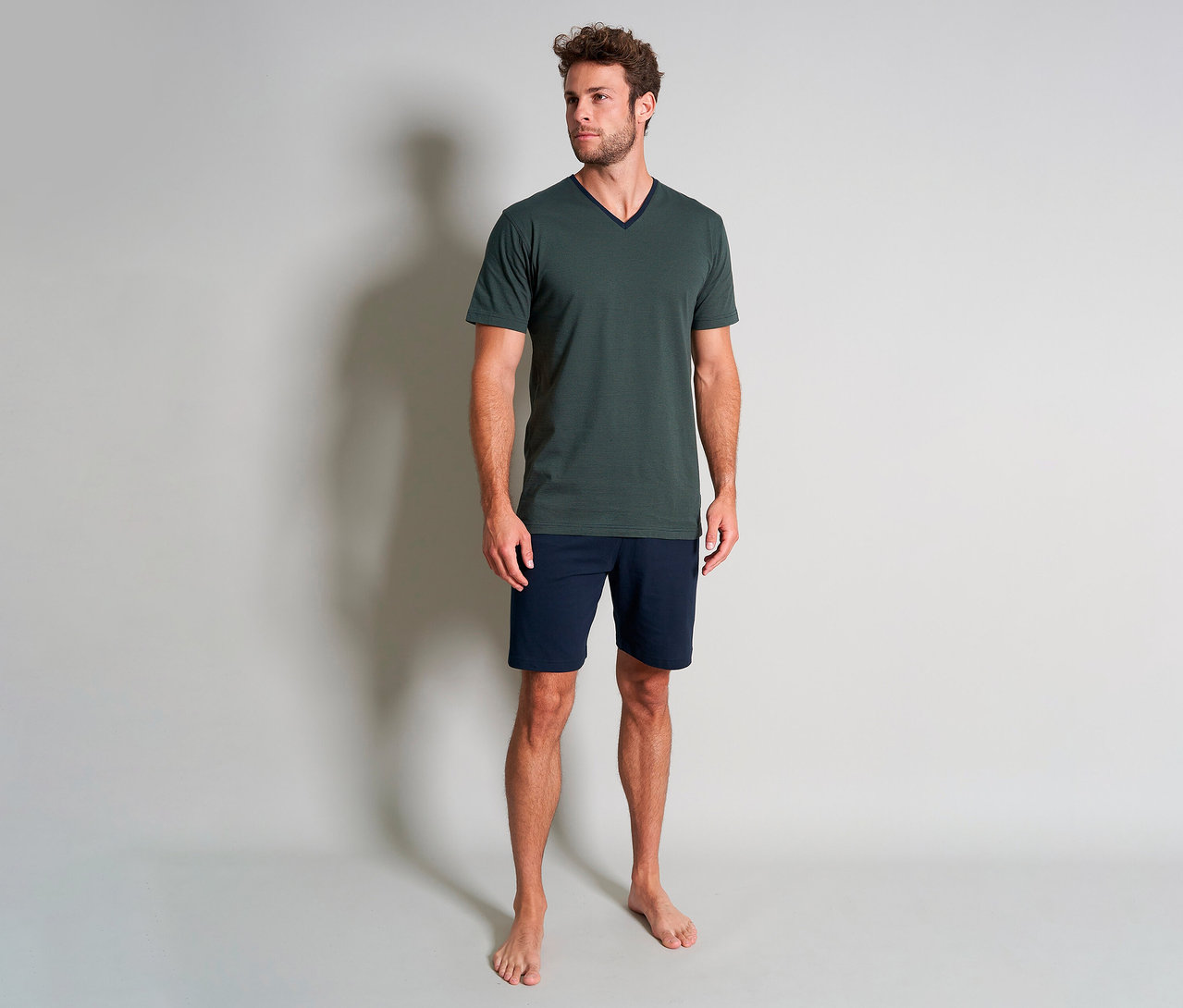 Férfi áll mezítláb a zöld Tom Tailor »Nevada« rövidnadrágos pizsamában.