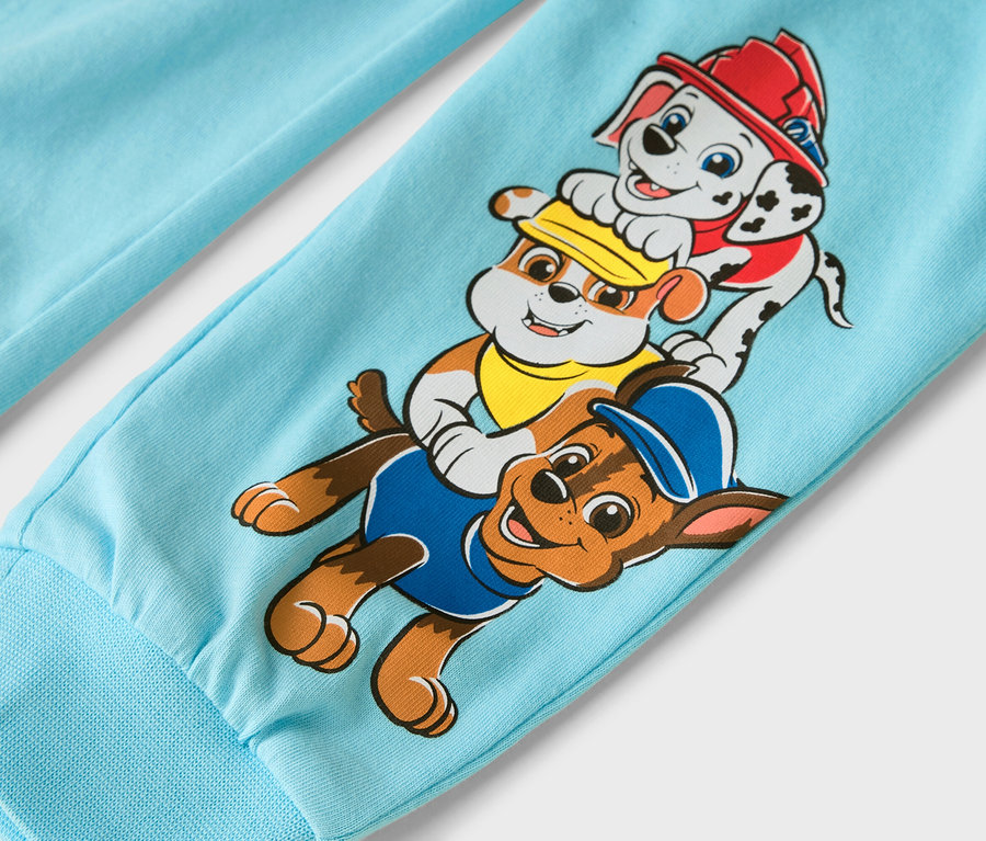 Egy világoskék nadrágszár közeli képe a Mancs Őrjárat szereplőivel: Marshall, Rubble és Chase.