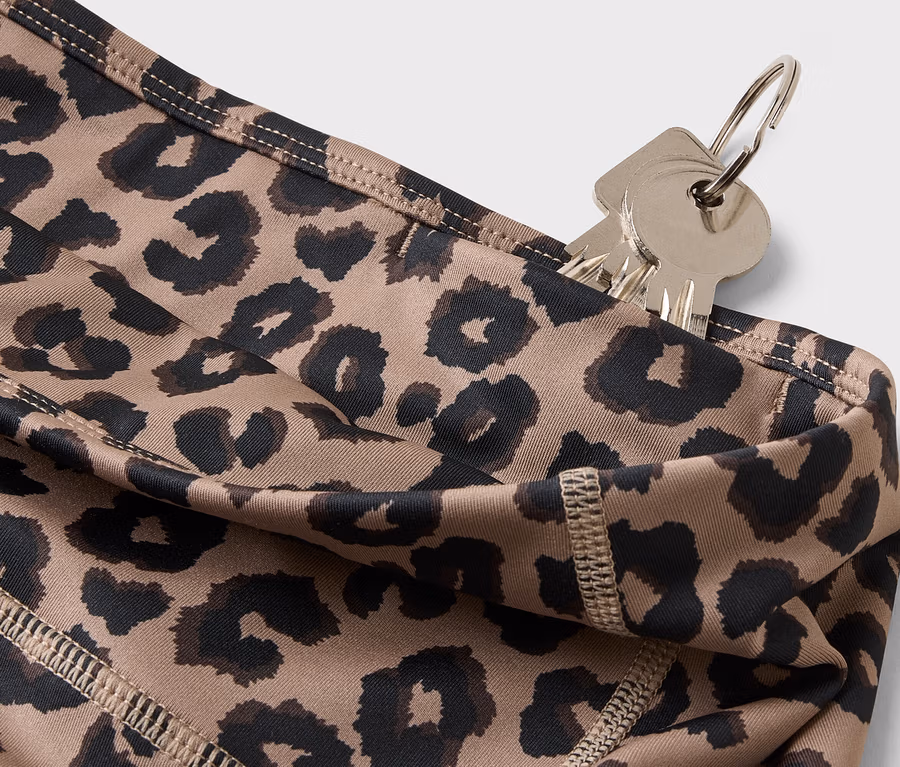 Közelkép egy kulcstartón lógó kulcsokról, amelyeket egy leopárdmintás leggings zsebébe csúsztattak.