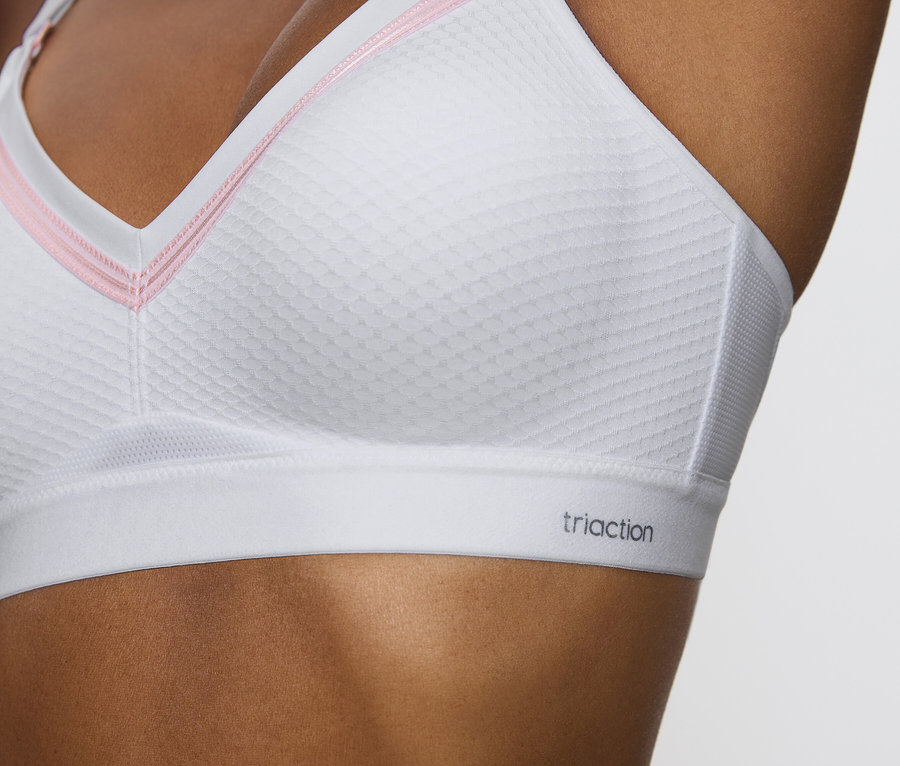 Egy nő közeli képe, aki fehér Triaction sportmelltartót visel.