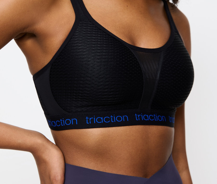 Közeli kép egy fekete Triaction sportmelltartót és sötétkék leggingset viselő nőről.