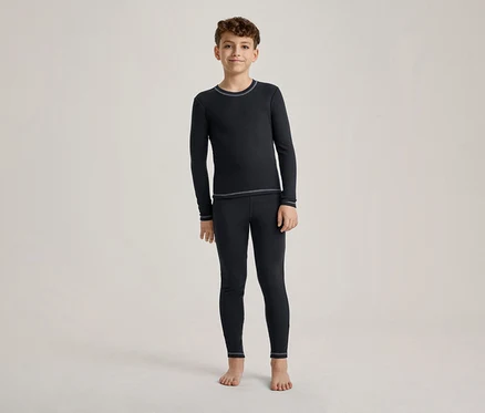 Egy fiú áll mezítláb, sötétkék hosszú ujjú pólót és hozzá illő leggingset visel világos varrásokkal.