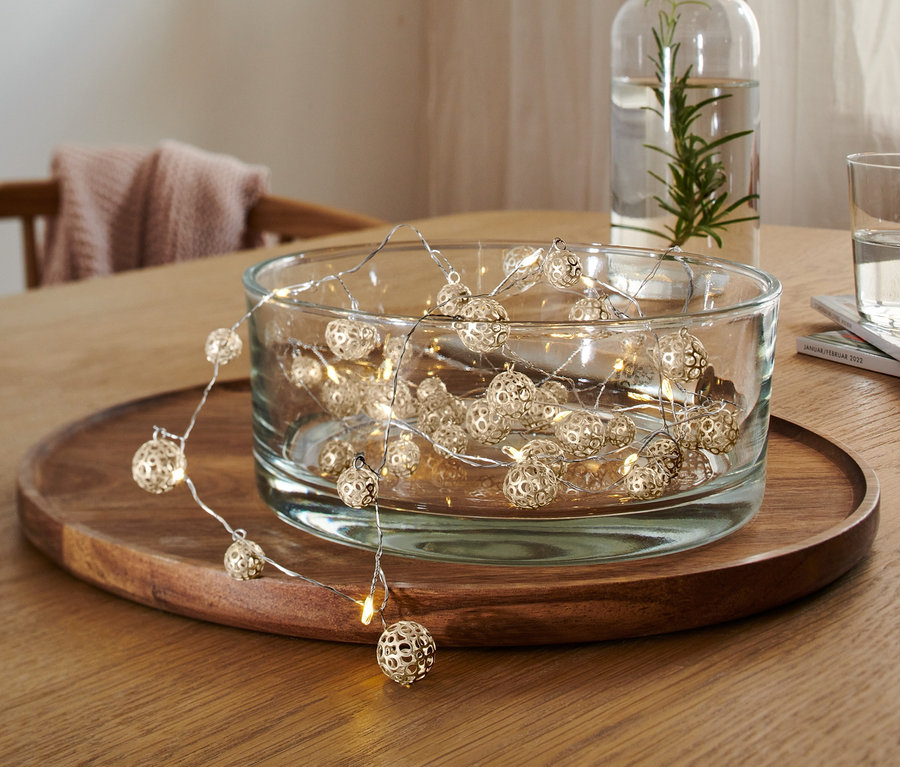 LED-es égősor, 38 gömb üvegtálban, fa asztalon.