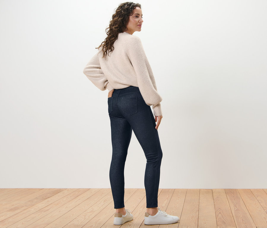 Nő farmerhatású bélelt leggingsben és pulóverben pózol.