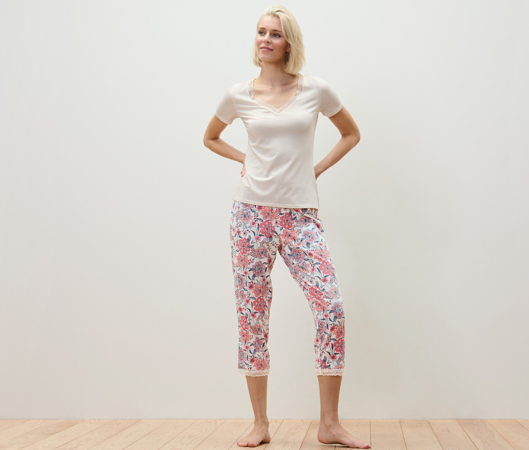 Nő pózol egy virágos mintázatú 7/8-os pizsamában.