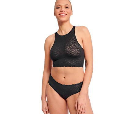 Mosolygó nő fekete, magas nyakú, hullámos szélű és texturált mintás bralette-et és fekete sloggi ZERO Feel Bliss hipszter alsót visel, hullámos széllel.