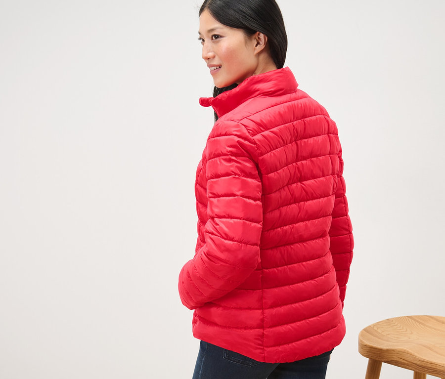 Nő visel egy piros, női steppelt dzsekit.