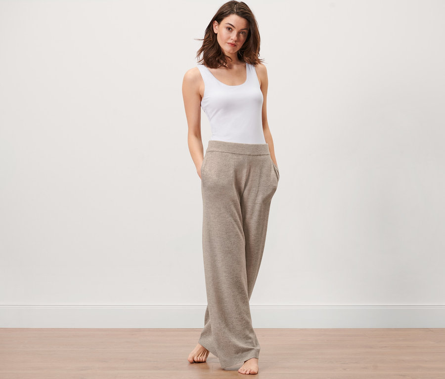 Egy nő áll, keze a kötött szabadidőnadrág zsebében.