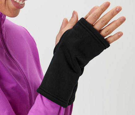 Nő rózsaszín kabátban fekete kézmelegítőt húz.