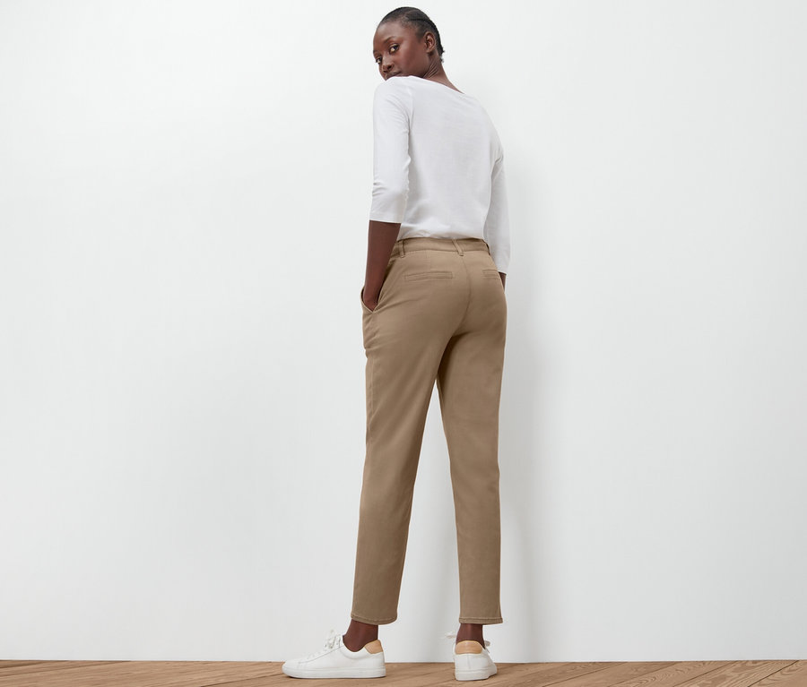 Egy nő háttal áll a kamerának, és bézs színű chino nadrágot visel.