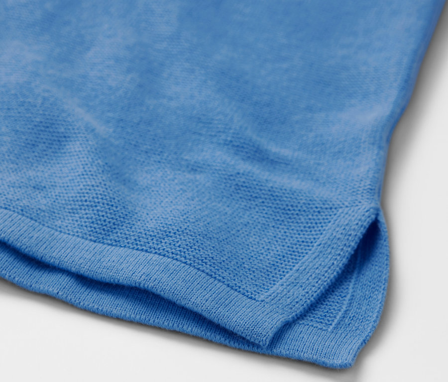 Világoskék kötött pulóver részlete.