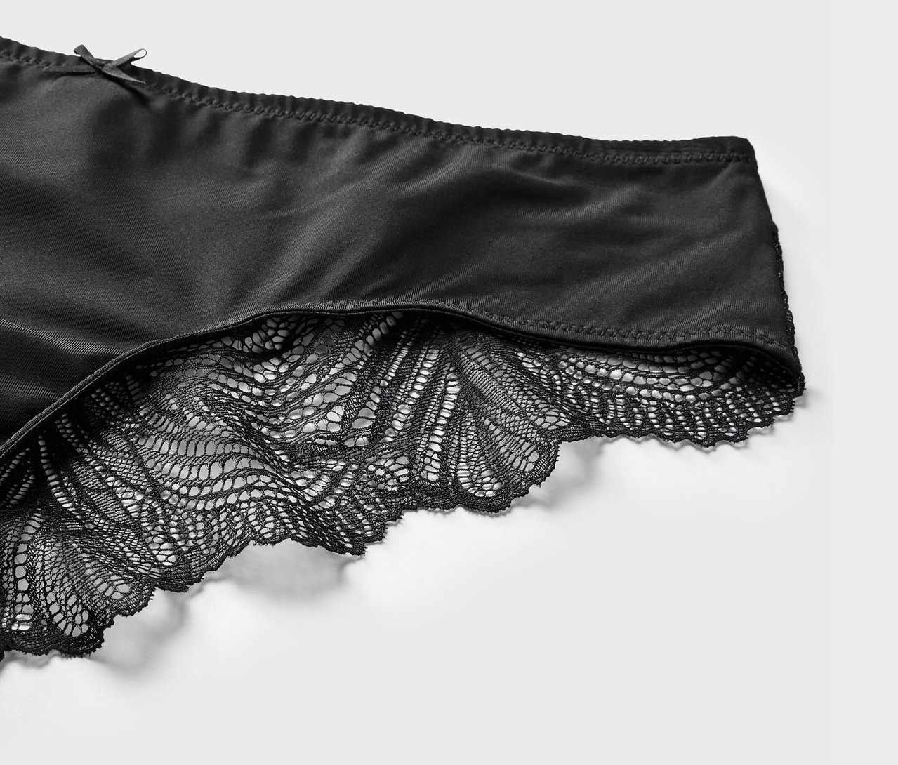 Egy fekete, csipkés brazil alsó részletfotója.