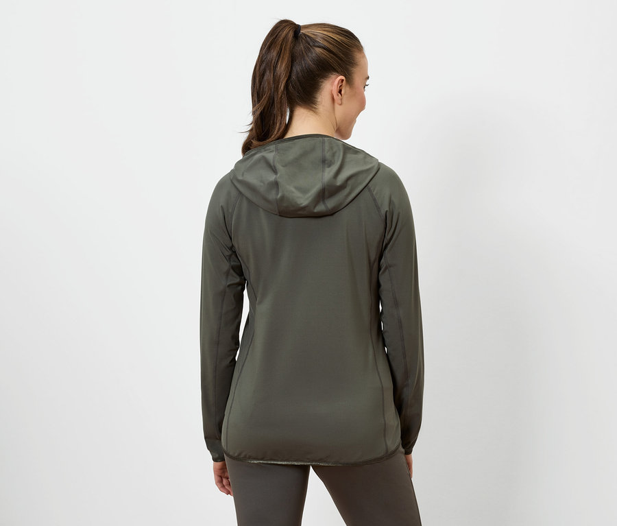 A barna haját lófarokba fogó nő olívazöld kapucnis kabátot és olívazöld leggingset visel.