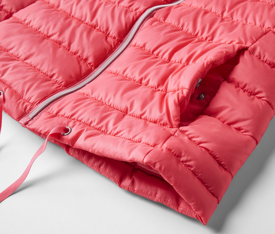 Egy rózsaszín, kapucnis steppelt mellény részlete, ezüst cipzárral.