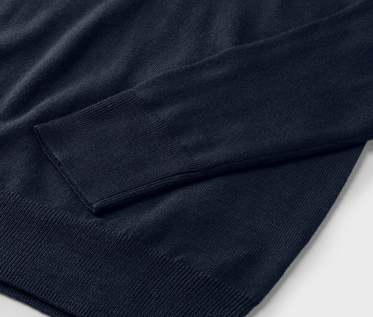 Egy sötétkék merinói kötött pulóver részletének közeli képe.