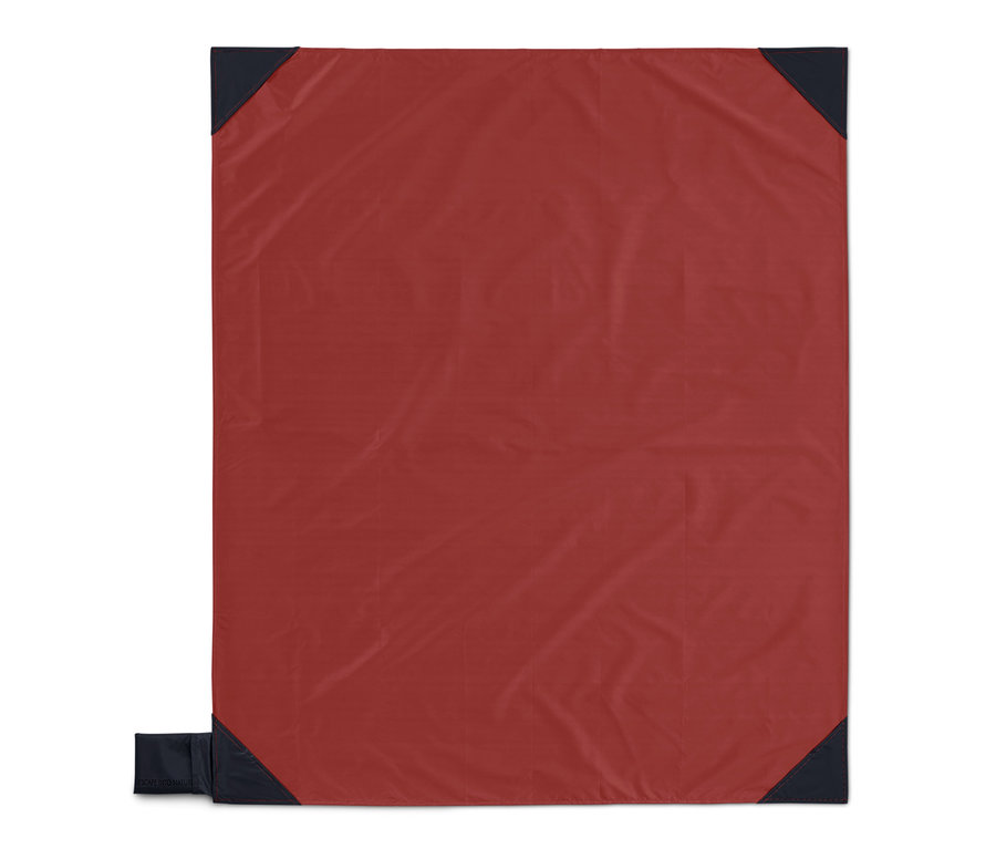 Egy piros mini pikniktakaró sötétkék sarkokkal.