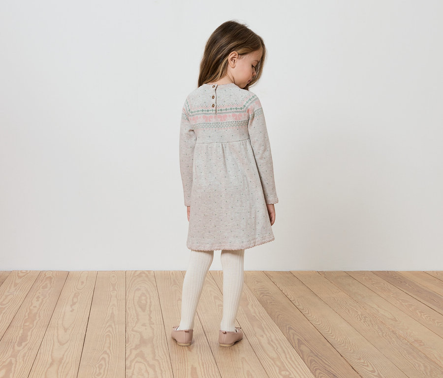 Hátulról látható lány hosszú ujjú ruhában.