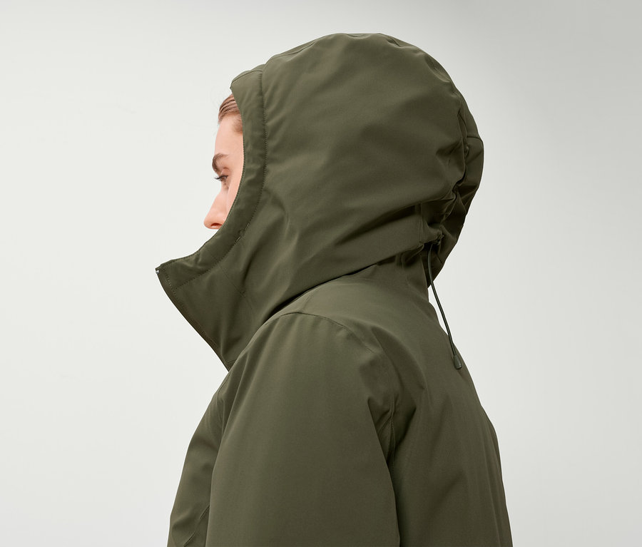 Egy nő profilja olívazöld kapucnis kabátban.