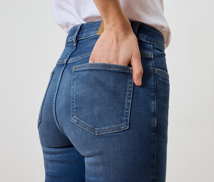 Nő kék farmernadrágjának hátsó zsebében tartja a kezét.