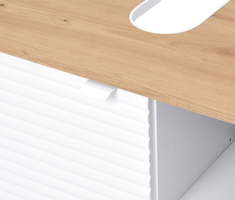 Egy világosbarna faasztal részletes képe, alatta egy fehér, barázdált fiókfronttal.