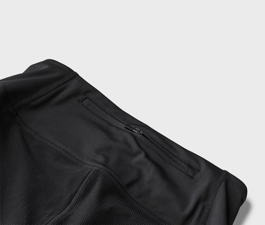 Egy fekete sportdzseki részletes nézete cipzáras zsebbel.