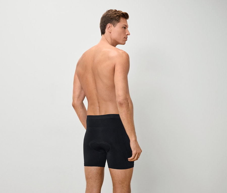 Hátulnézet egy meztelen felsőtestű férfiról, aki fekete boxeralsót visel.