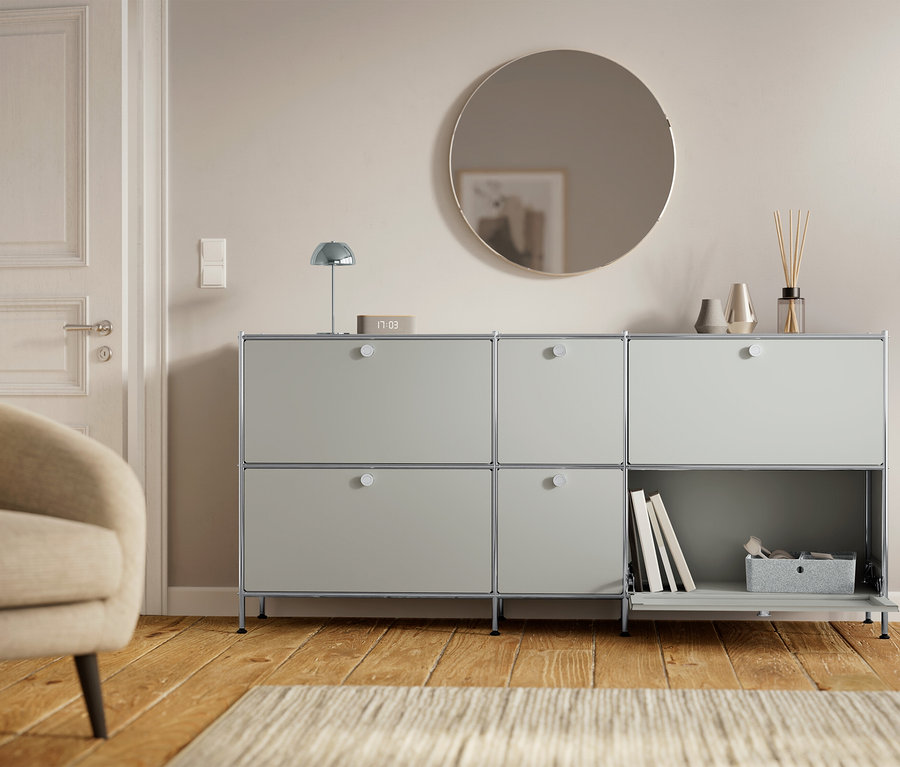 Egy szürke szekrény hat rekesszel áll egy ajtó és egy fotel mellett.