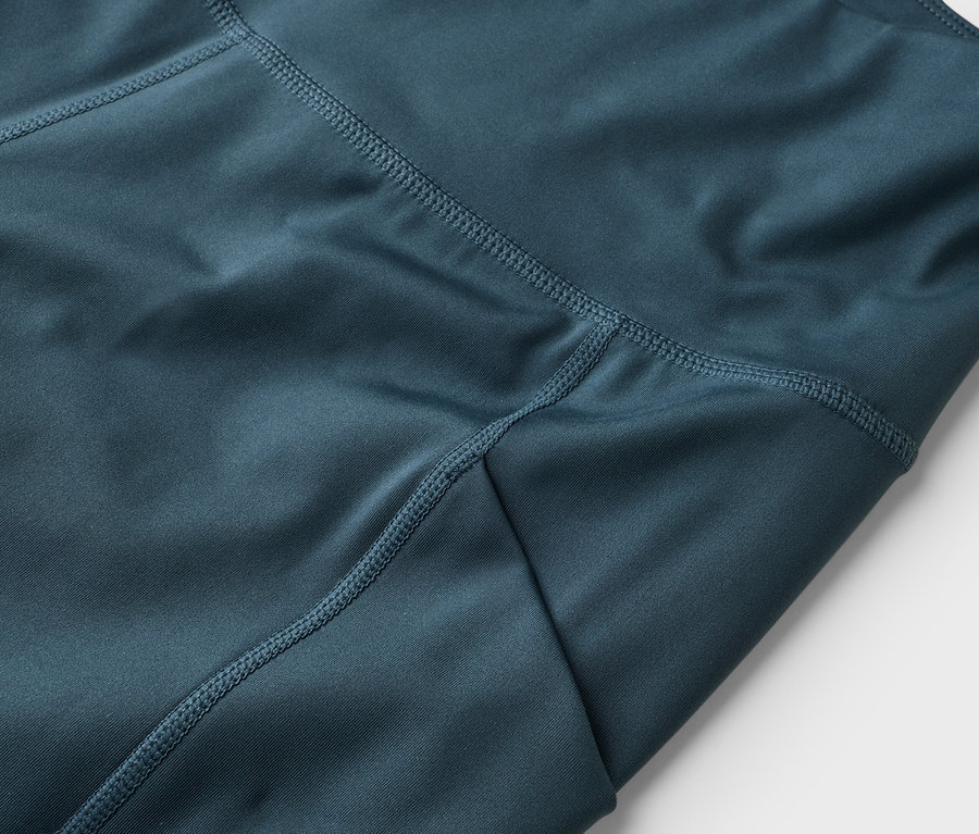 Kék leggings közeli képe, látható varratokkal.