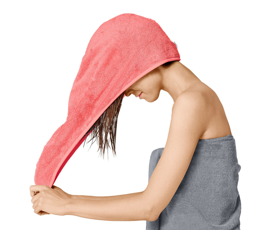 Egy nő turbán alakú törölközőt teker a nedves hajára.