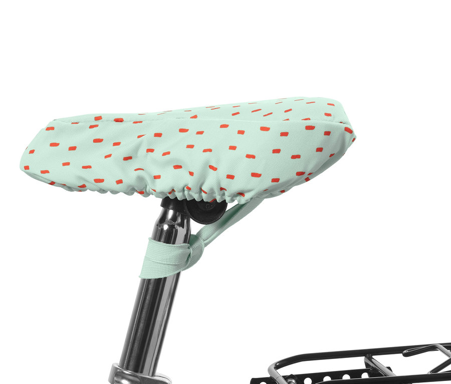 Egy zöld, piros téglalapokkal mintázott gyerek kerékpáros üléshuzat látható.
