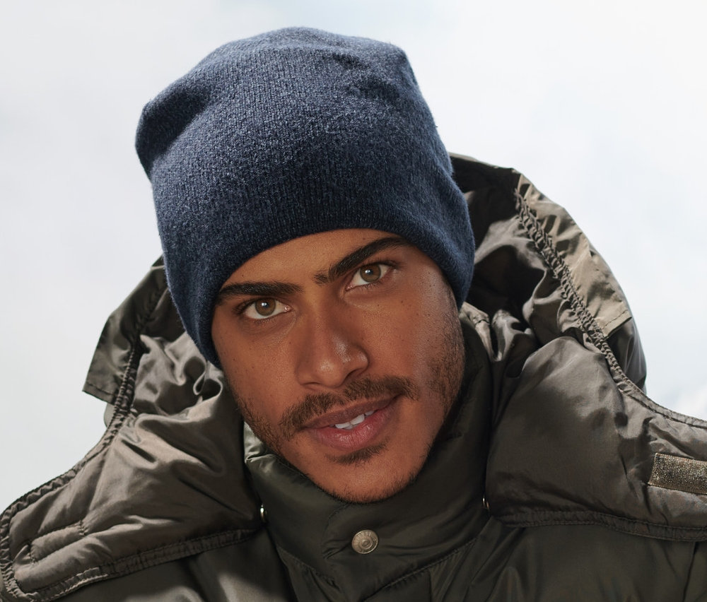 Egy férfi ül a padon, sötétkék kötött sapkát visel.