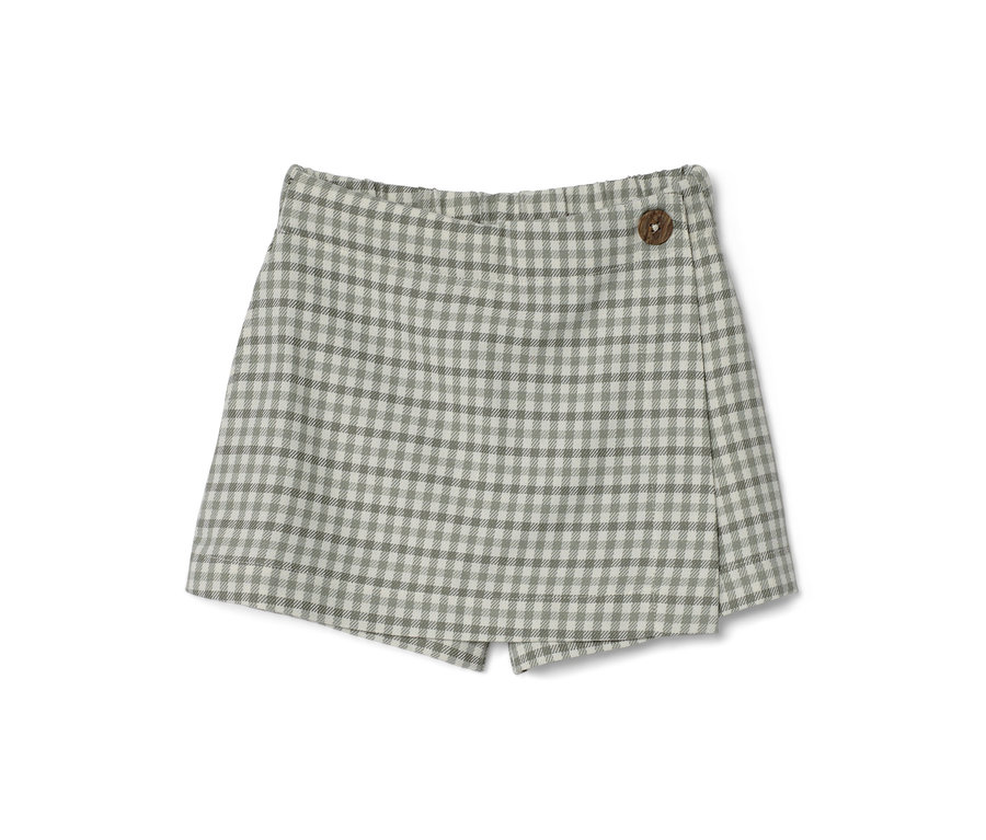 Egy kislány kockás nadrágszoknya fa gombbal.