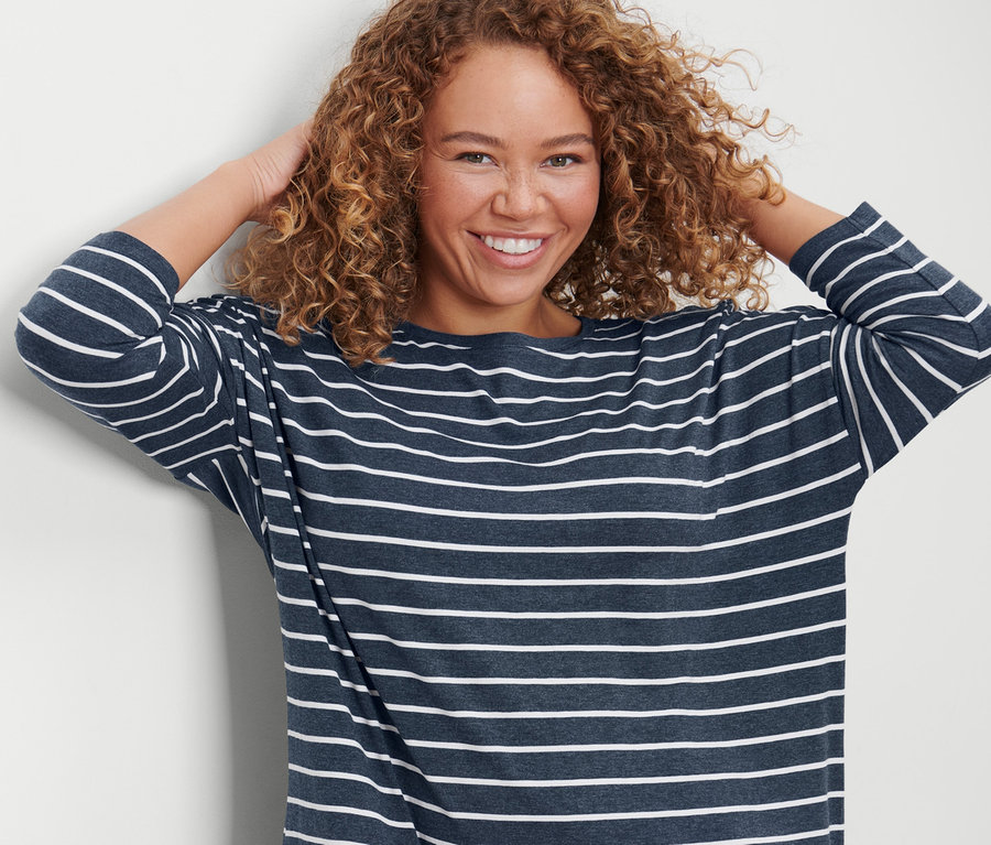 Mosolygó nő pózol egy kék-fehér csíkos hálóingben.