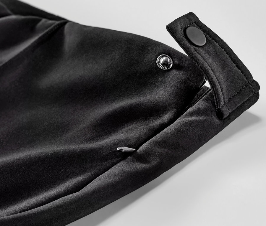 Egy fekete női softshell sínadrág részlete cipzáras zsebbel és patentos zárással.