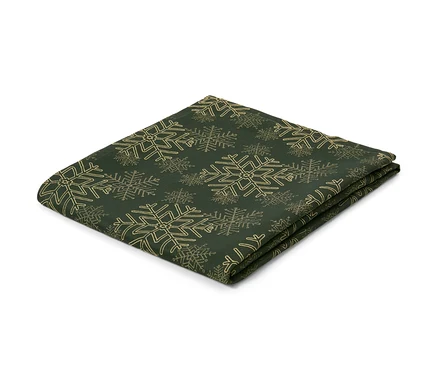 Egy zöld, hópehely mintás jacquard asztalterítő összehajtva, fehér háttér előtt.