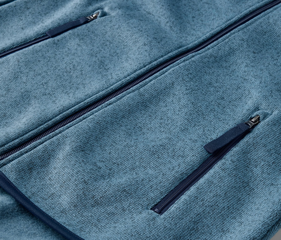 Kék kötött polár pulóver részlete cipzáras zsebekkel.