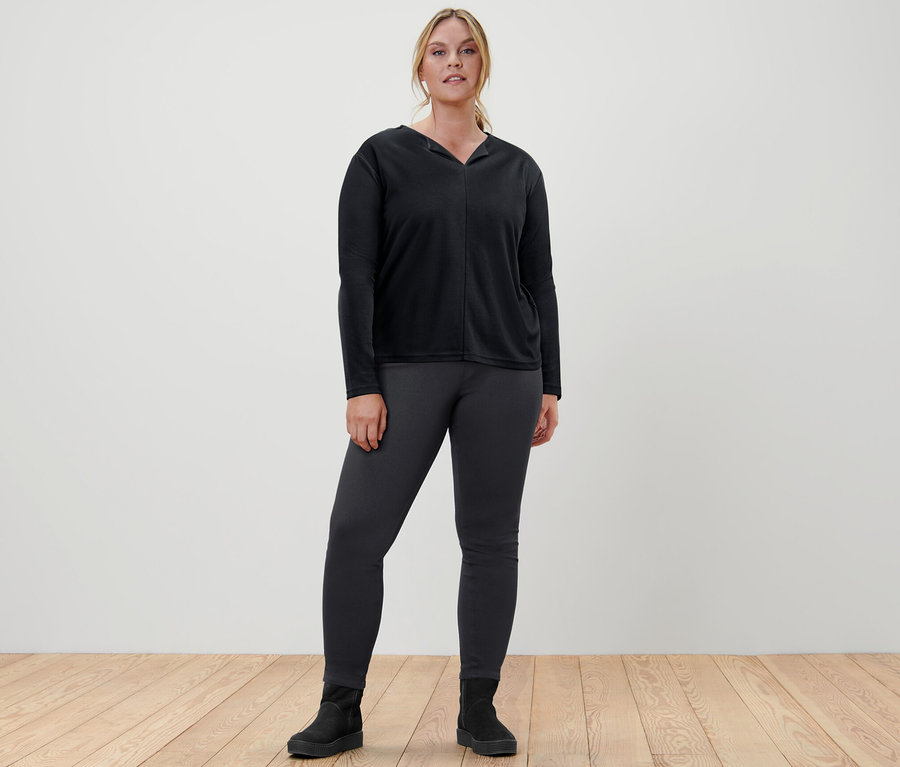 Nő áll fekete pólóblúzban és leggingsben.