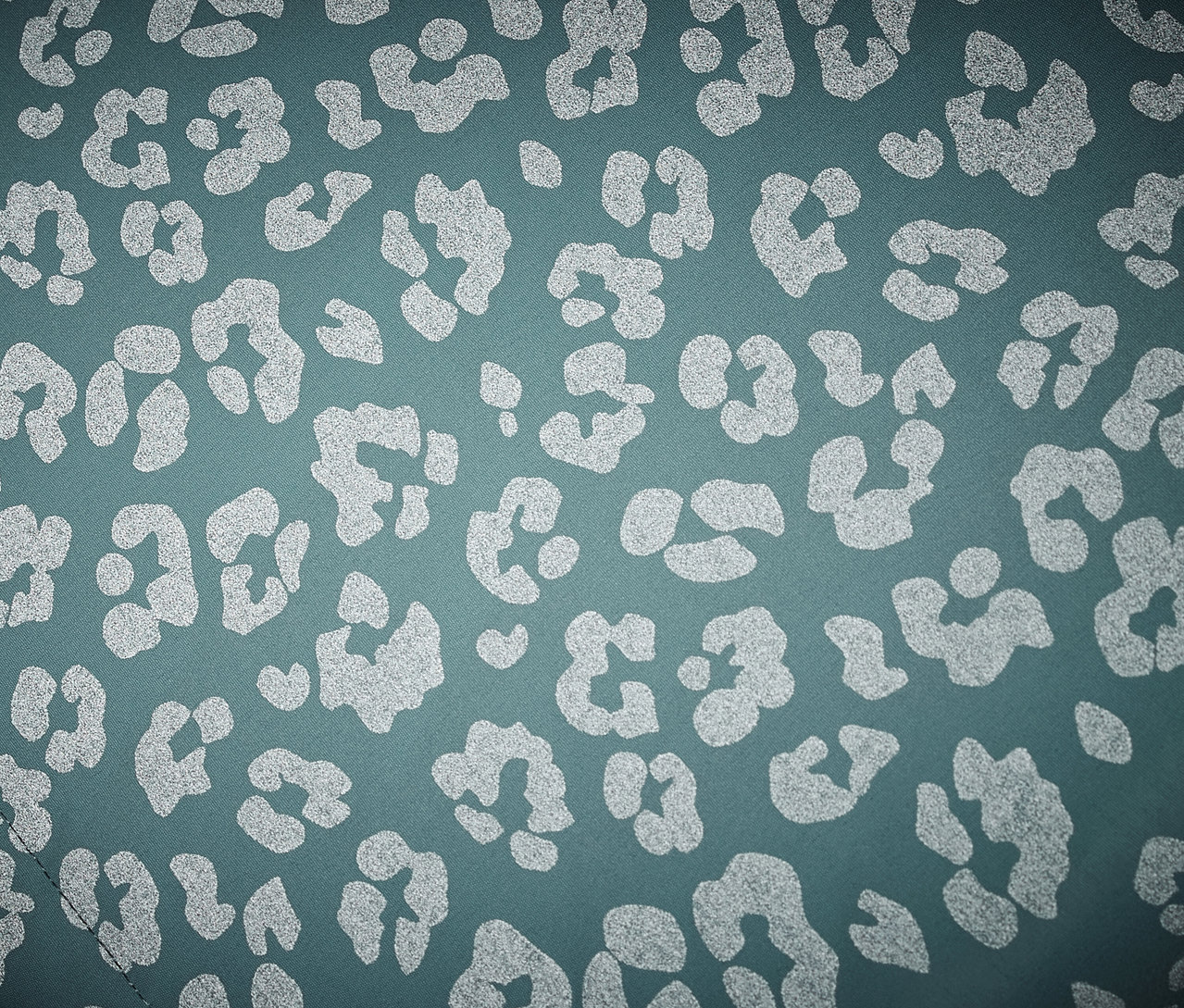 Egy gyerek termo esőkabát közeli képe, fényvisszaverő elemekkel, leopárd mintával.