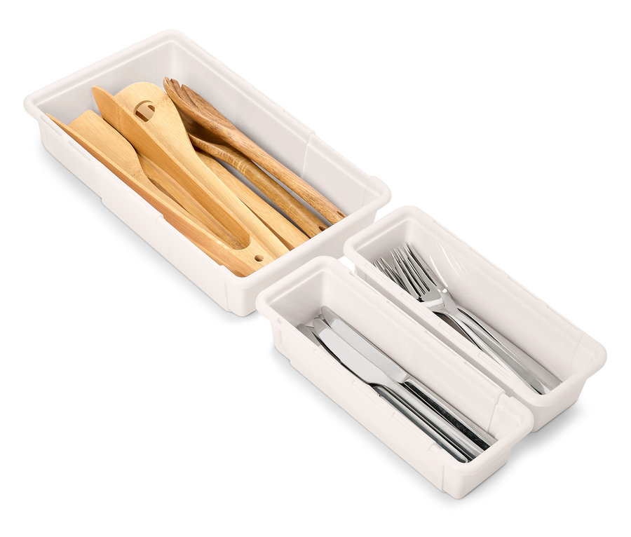 Fehér fiókos szervezőkészletek fa és ezüst konyhai eszközökkel.