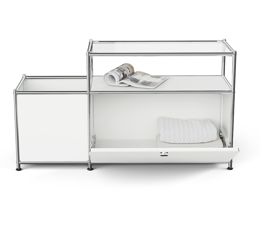 Fehér moduláris tárolórendszer nyitott polcokkal és egy fiókkal, a felső polcon egy magazinnal, a fiókban összehajtott textíliákkal.