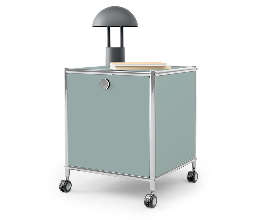 Szürke lámpa és könyv egy kékeszöld tárolódobozon, görgőkön.