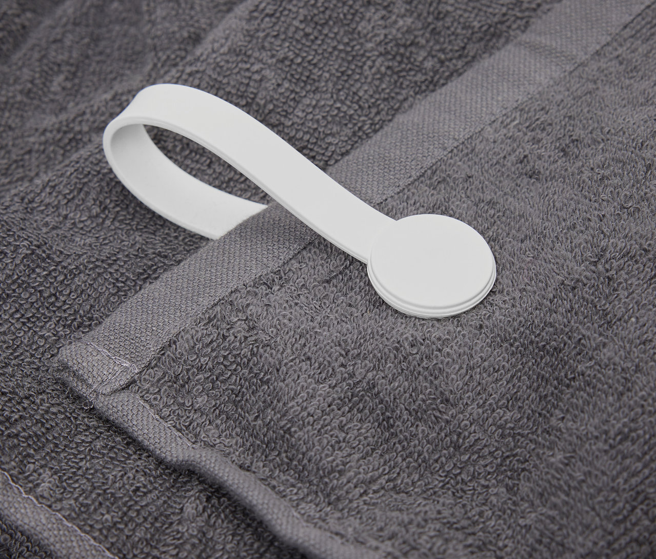 Egy szürke törölköző részlete fehér akasztóval.