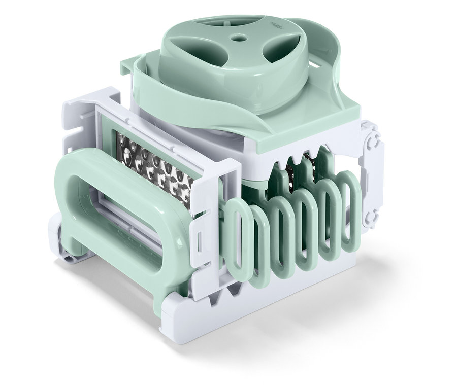 Közelkép egy pasztellzöld és fehér konyhai zöldségszeletelőről.