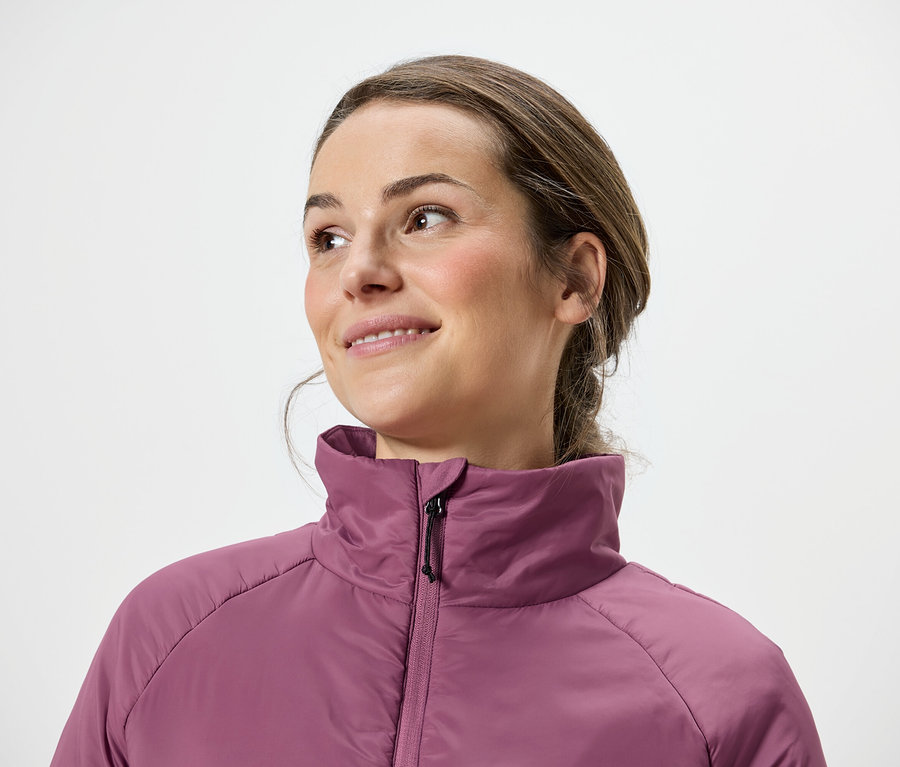 Barna hajú, rózsaszín kabátos nő jobbra néz.