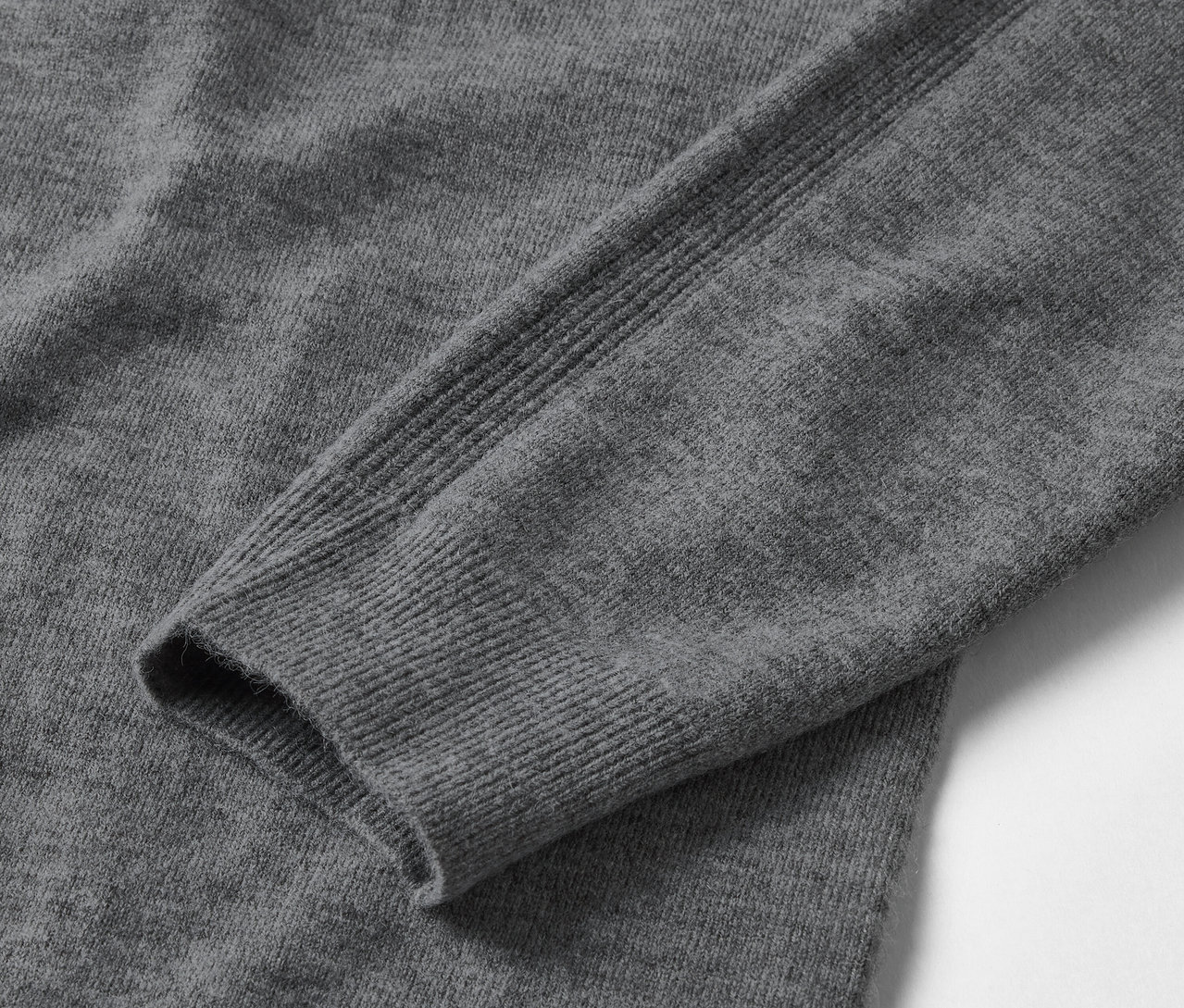Egy szürke, hosszú ujjú pulóver részlete.