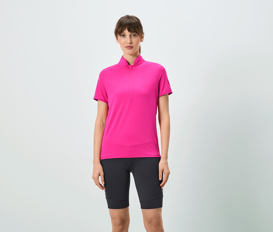 Nő visel rózsaszín, rövid cipzáras pólót és fekete rövidnadrágot.