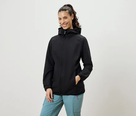 Mosolygó, copfos nő visel fekete softshell kabátot és kék nadrágot.