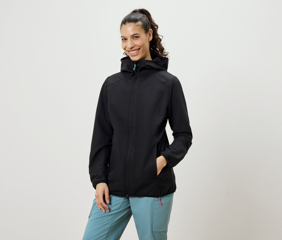 Mosolygó, copfos nő visel fekete softshell kabátot és kék nadrágot.