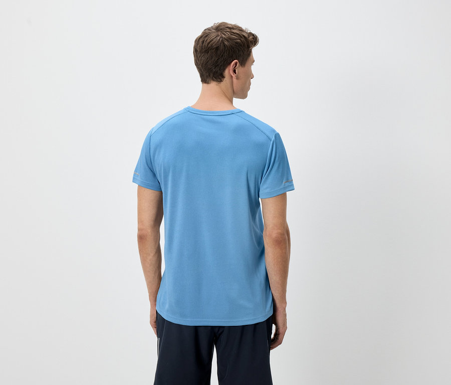 Hátulnézet egy világosbarna hajú férfiról, aki kék pólót és fekete rövidnadrágot visel fehér háttér előtt.